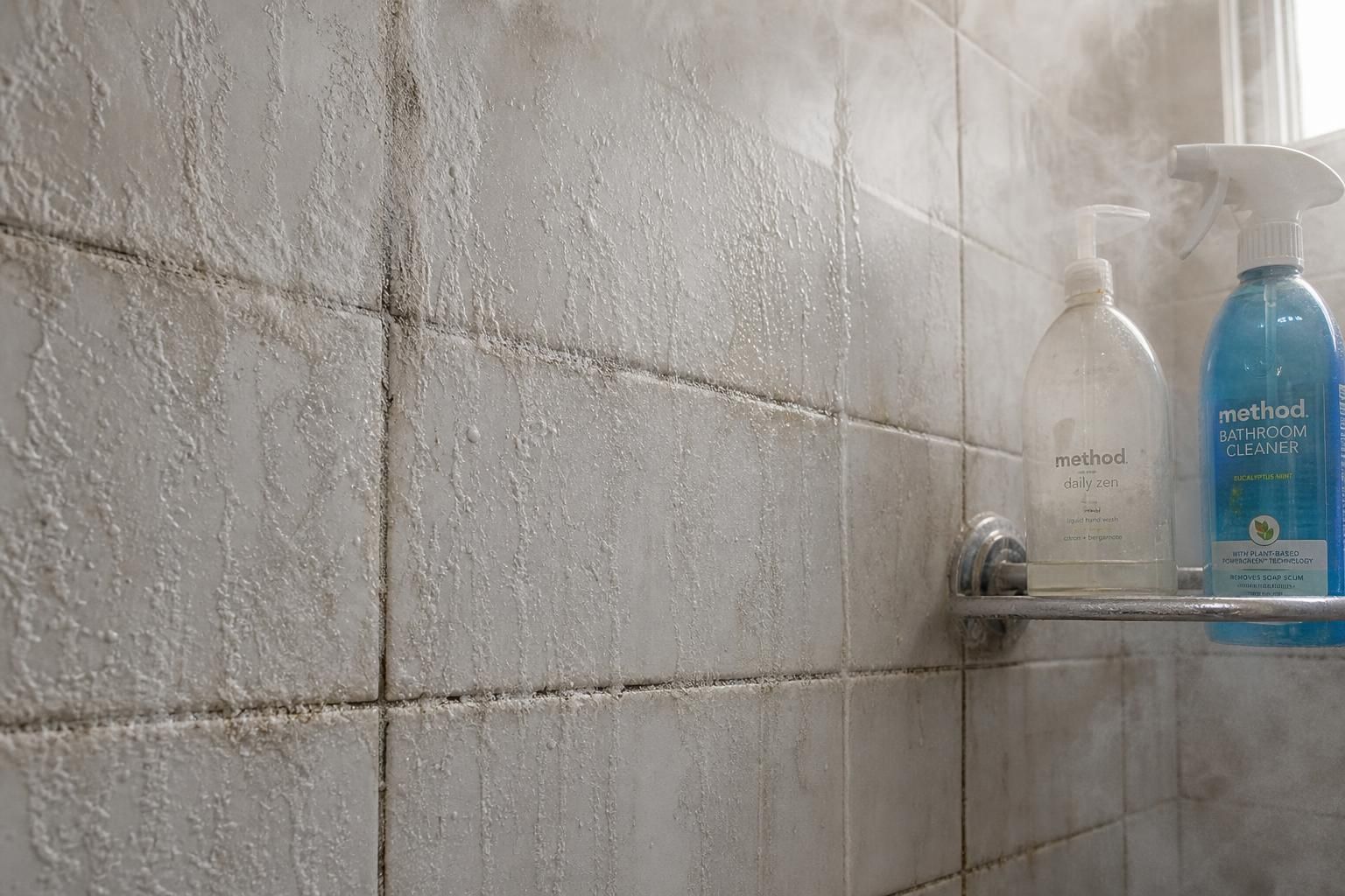 A shower wall covered in thick soap scum and mineral deposits.